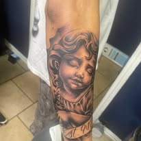 Cherub portrait tattoo on a forearm, work by E at I-45 Ink