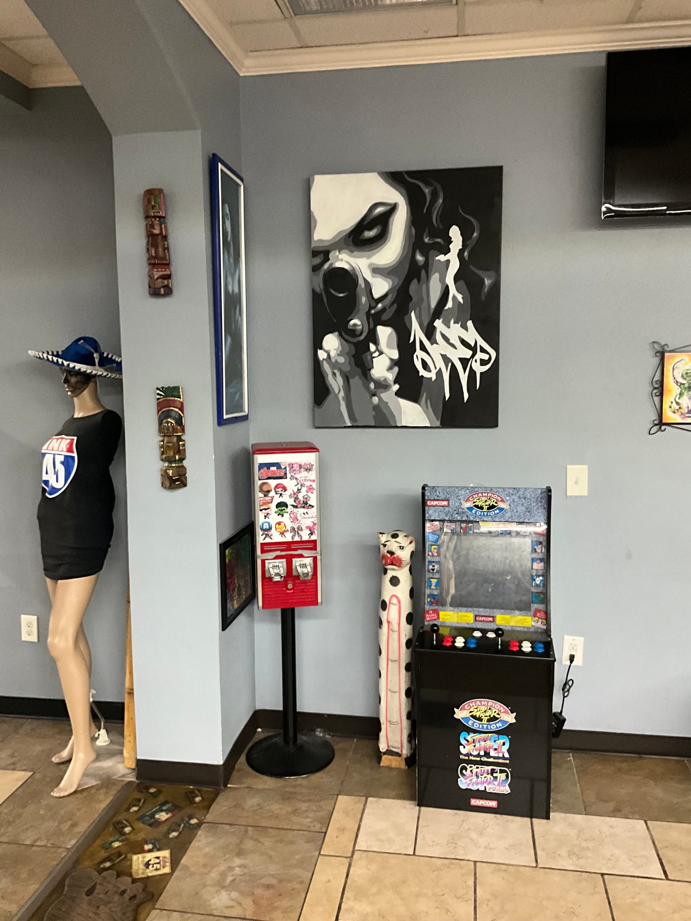 Lobby area of I-45 Ink with a Street Fighter II arcade cabinet, tattoo flash art, and a mannequin wearing an I-45 Ink shirt