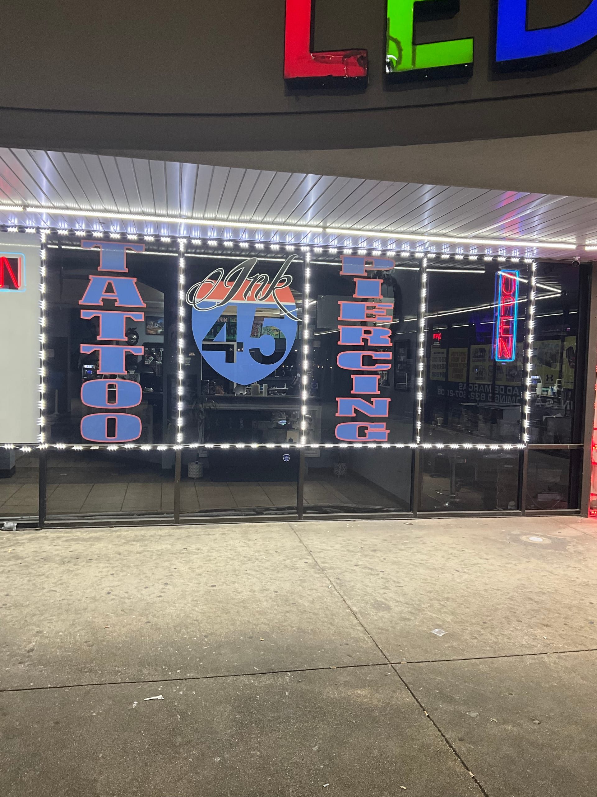 I-45 Ink storefront at dusk showing the Tattoo, Ink 45, and Piercing window lettering